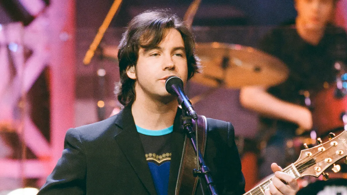 Duncan Sheik joven cantando y tocando la guitarra sobre un escenario